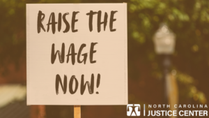 "Raise the wage NOW!" on protest sign. 